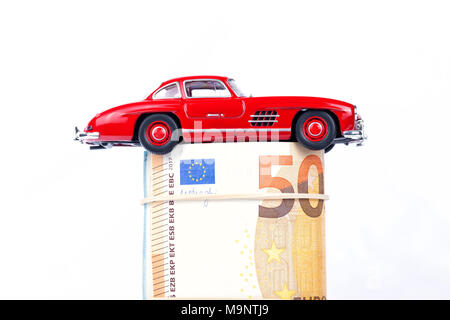 Un classico auto sportiva dell'anno 1954 di colore rosso su euro bills isolati su sfondo bianco. Foto Stock