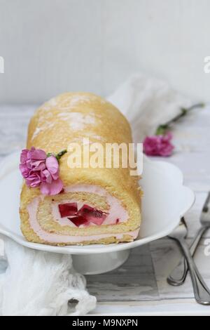 Jelly Roll torta con garofani rosa fiori su sfondo bianco Foto Stock