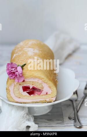 Jelly Roll torta con garofani rosa fiori su sfondo bianco Foto Stock