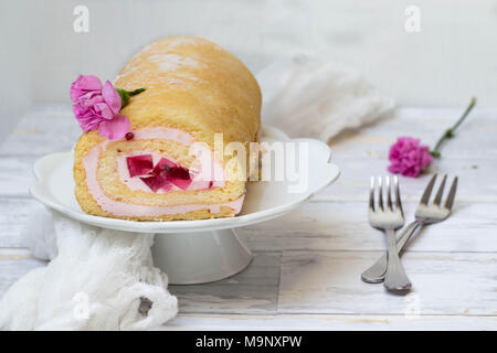 Jelly Roll torta con garofani rosa fiori su sfondo bianco Foto Stock