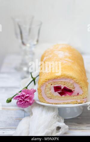 Jelly Roll torta con garofani rosa fiori su sfondo bianco Foto Stock