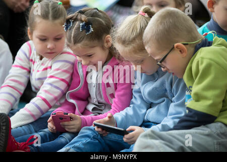 La Bielorussia, Gomel, 2 novembre 2017. Apertura della Biblioteca dei bambini.bambina sta cercando in un telefono cellulare. Bambina sta giocando in un telefono cellulare Foto Stock