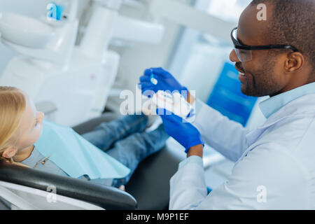 Sorridente dentista maschio che mostra il corretto algoritmo di pulizia dei denti Foto Stock