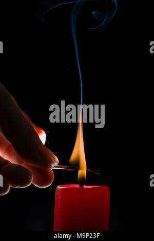Accensione di una candela con un match di fronte a uno sfondo nero, studio shot Foto Stock