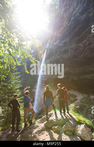 Un gruppo di giovani in piedi al piede della cascata Pericnik in alpine valle di Vrata vicino a Mojstrana nel Parco Nazionale del Triglav, Slovenia Foto Stock