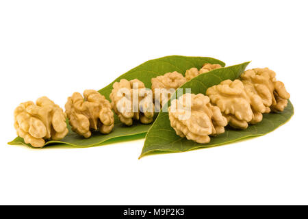 Giallo chiaro nucleo di noce close-up con buccia e lascia impilate a isolare la composizione su sfondo bianco Foto Stock