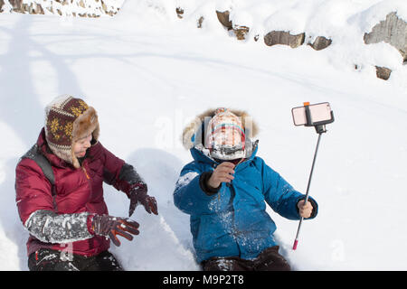 Una giovane coppia è giocare nella neve in Seoraksan National Park, Gangwon-do, la Corea del Sud. La ragazza appena buttato una palla di neve nel volto del suo ragazzo amico, chi è catturare con uno smart phone su un bastone selfie. Seoraksan è un bellissimo e iconico Parco Nazionale delle montagne vicino Sokcho nella regione del Gangwon-do di Corea del Sud. Il nome si riferisce a balze innevate montagne. Insieme contro il paesaggio sono due templi buddisti: Sinheung-sa e Beakdam-sa. Questa regione è di ospitare le Olimpiadi invernali nel febbraio 2018. Seoraksan è un bellissimo e iconico Parco Nazionale delle montagne vicino Sokcho nella Foto Stock
