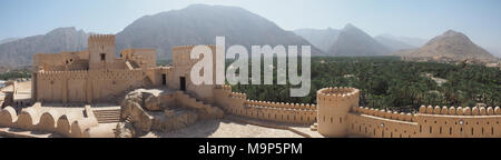 Fortezza Nakhl con torre rotonda e merlature, sul retro Hajar Montagne, Vista panoramica, Nakhl, Oman Foto Stock