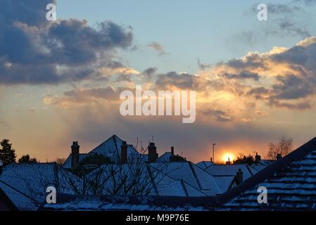 Tramonto spettacolare attraverso la raccolta di nuvole di neve su tetti suburbana Foto Stock