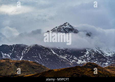 Picco di Mount Snowdon nel Wales UK parzialmente coperto da cloud e neve Foto Stock