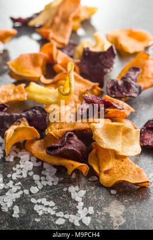 Fritto misto di chip di vegetali e sale sulla vecchia tabella. Foto Stock