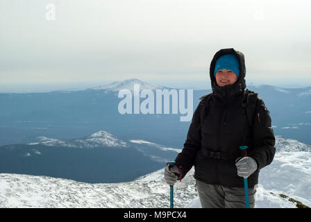 Traveler donna con i bastoncini per il nordic walking o bastoncini da sci in mani contro uno sfondo di un inverno paesaggio di montagna Foto Stock