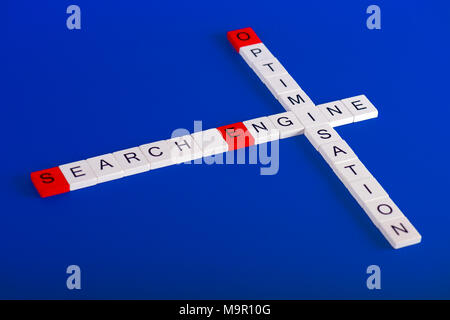 Ottimizzazione dei motori di ricerca (SEO) in bianco dei blocchi di legno su sfondo blu in stile cruciverba, prime lettere sono di colore rosso Foto Stock