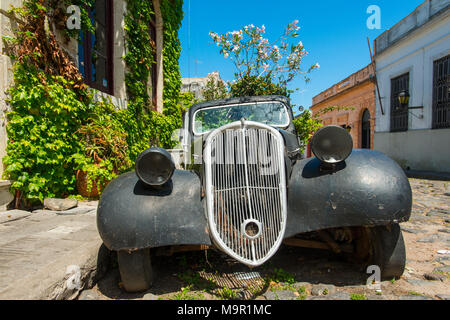 Auto rottamata di oldtimer ricoperta con piante fiorite, Colonia del Sacramento, Uruguay Foto Stock