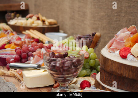 Una luminosa e colorata selezione di frutta, formaggi, salse, salumi e cracker sparsi in una bella lastra di legno. Foto Stock