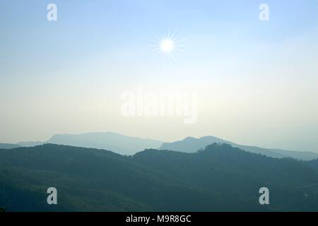 Strato di picchi di montagna ricoperta di boschi di conifere boschi di latifoglie in mattinata,mattina paesaggio di montagna con onde di nebbia . Foto Stock