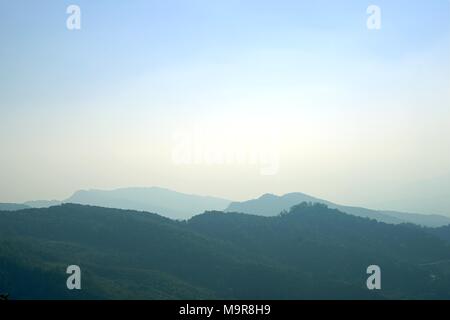 Strato di picchi di montagna ricoperta di boschi di conifere boschi di latifoglie in mattinata,mattina paesaggio di montagna con onde di nebbia . Foto Stock
