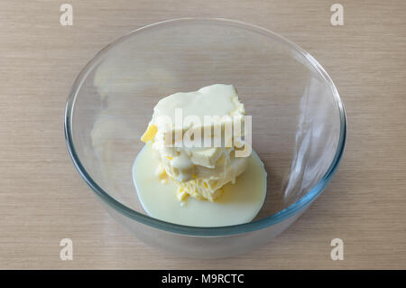 Ciotola con ingredienti di latte condensato e il burro per la cottura di crema di burro in conformità con la ricetta casalinga Foto Stock