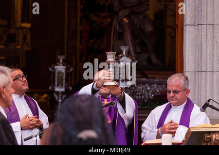 Il sacerdote che celebra la Messa, tenendo in mano un calice di vino, fuori la Ermita de la Viña in Adeje old town, Tenerife, Isole Canarie, Spagna Foto Stock