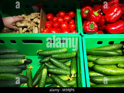 Nella vetrina di un negozio diversi ortaggi giacciono in scatole e la persona sceglie le verdure. Foto Stock