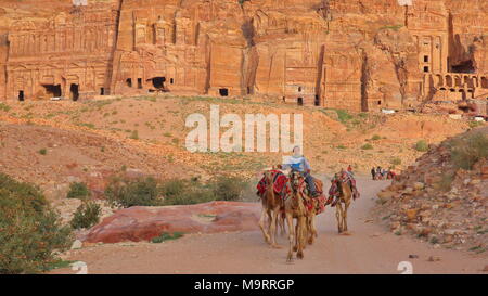 PETRA, GIORDANIA - Marzo 7, 2016: un beduino in sella al suo cammello con le tombe reali in background Foto Stock