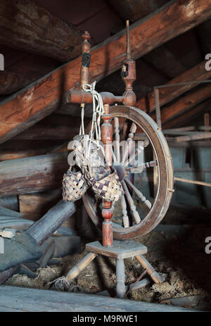 Vintage russo casalinghi. Ancora in vita. Vecchia ruota di filatura e bast scarpe in un polveroso garret nella casa di campagna. Messa a fuoco selettiva. Foto Stock