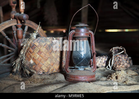 Vintage russo casalinghi. Ancora in vita. Vecchia ruota di filatura, liberiane scarpe e una lampada di kerosene in un polveroso garret nella casa di campagna. Focu selettiva Foto Stock