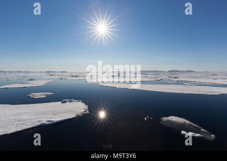 Il sole di mezzanotte oltre l'Oceano Artico con il drifting ice floes, a nord del Circolo Polare Artico a Nordaustlandet, Svalbard / Spitsbergen, Norvegia Foto Stock