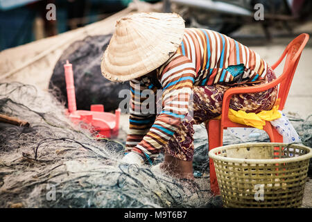 Donna vietnamita riparazione rete da pesca Foto Stock