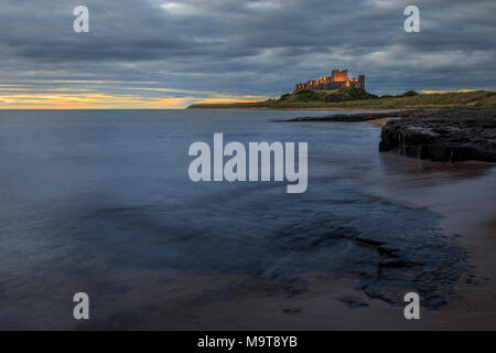 Il castello di Bamburgh alba sul litorale di Northumberland Foto Stock