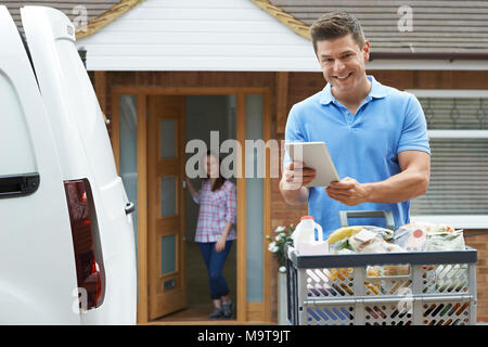 Ritratto di autista consegna Online negozio di generi alimentari per la casa usando la tavoletta digitale Foto Stock