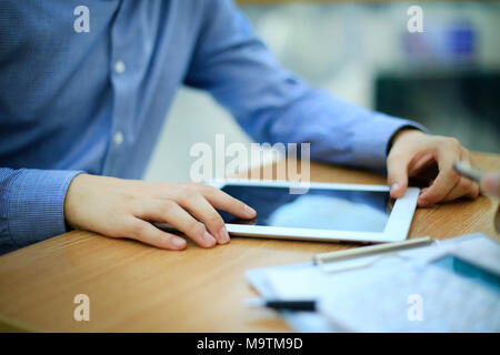Chiudere fino a mani uomo multitasking utilizzando tablet portatile, connessione wifi Foto Stock