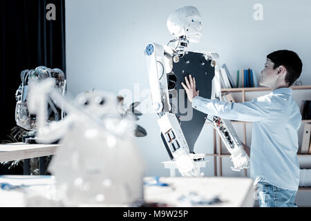 Stupiti giovane toccando il petto di macchina robotica Foto Stock