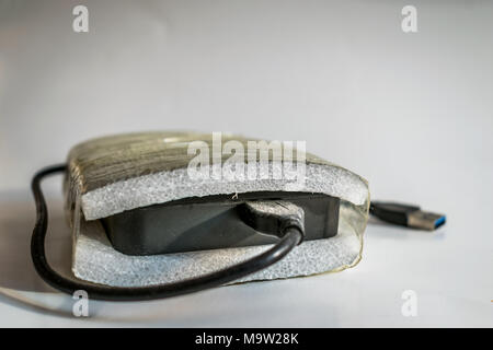 Una pesante storage disco rigido ben protetti dalla gomma espansa lacerata attorno ad esso con sfondo bianco Foto Stock