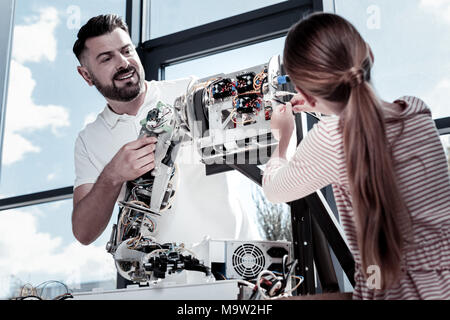 Orgoglioso insegnante guardando studentessa lavorando su robot Foto Stock