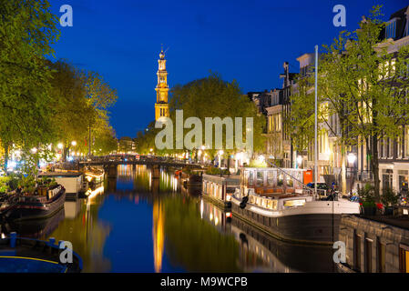 Bella notte a Amsterdam. Illuminazione notturna degli edifici e barche vicino all'acqua nel canale. Foto Stock