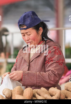 Pechino-Aprile 8, 2008. Femmina fornitore del mercato vende patate su un mercato. Molti vecchi mercati tradizionali verrà arrestato dal governo. Foto Stock
