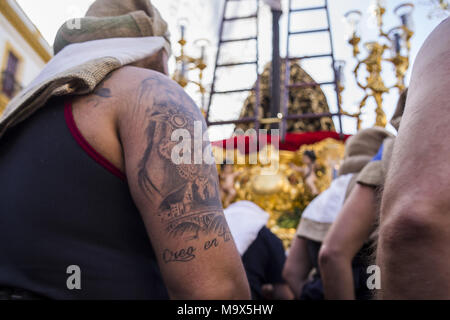 Siviglia, Spagna. 28 Mar, 2018. Un costalero di fratellanza chiamato ''El Baratillo'' indossare un tatuaggio con il volto della Vergine Maria e le parole " Io credo in voi" durante la sua sfilata alla Cattedrale il Mercoledì Santo. Credito: Daniel Gonzalez Acuna/ZUMA filo/Alamy Live News Foto Stock