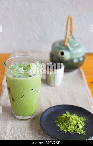 Iced il tè verde e il tè verde in polvere sul piatto nero con tè pentola di sfondo Foto Stock