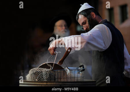 Un ebreo di Haredi immergere gli utensili da cucina in acqua bollente in un processo chiamato Hagalat Kelim (utensili da kashering) per rimuovere i resti di lievito mentre si preparano per la festa ebraica di Pesach (Pasqua) nel quartiere di Mea Shearim, un'enclave ultra-ortodossa in Israele di Gerusalemme occidentale. Gli ebrei trascorrono le settimane prima della Pasqua in una raffica di fuse complete, per rimuovere ogni morsel di cibi lievitati che sono proibiti nella festa ebraica della Pasqua. Foto Stock