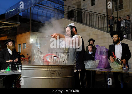 Un ebreo di Haredi immergere gli utensili da cucina in acqua bollente in un processo chiamato Hagalat Kelim (utensili da kashering) per rimuovere i resti di lievito mentre si preparano per la festa ebraica di Pesach (Pasqua) nel quartiere di Mea Shearim, un'enclave ultra-ortodossa in Israele di Gerusalemme occidentale. Gli ebrei trascorrono le settimane prima della Pasqua in una raffica di fuse complete, per rimuovere ogni morsel di cibi lievitati che sono proibiti nella festa ebraica della Pasqua. Foto Stock