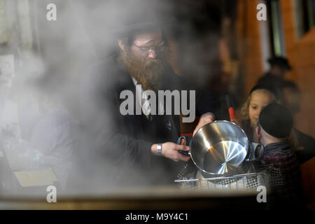 Un ebreo di Haredi immergere gli utensili da cucina in acqua bollente in un processo chiamato Hagalat Kelim (utensili da kashering) per rimuovere i resti di lievito mentre si preparano per la festa ebraica di Pesach (Pasqua) nel quartiere di Mea Shearim, un'enclave ultra-ortodossa in Israele di Gerusalemme occidentale. Gli ebrei trascorrono le settimane prima della Pasqua in una raffica di fuse complete, per rimuovere ogni morsel di cibi lievitati che sono proibiti nella festa ebraica della Pasqua. Foto Stock