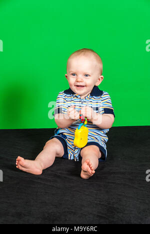 Felice di 10 mesi Baby Boy su schermo verde giocando con il giocattolo Foto Stock