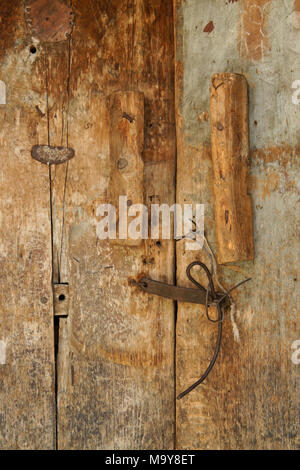 Vecchia porta di legno con vernice sbiadita e rusty hardware Foto Stock