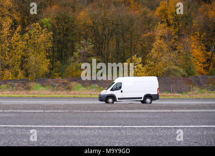 Commerciale cargo compatto mini van veicolo per small business va in ingresso alla strada interstatale con autunno giallo oro alberi sullo sfondo Foto Stock