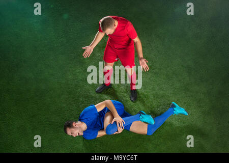 Maschio di giocatore di calcio che soffrono di lesioni della gamba sul calcio Campo verde Foto Stock