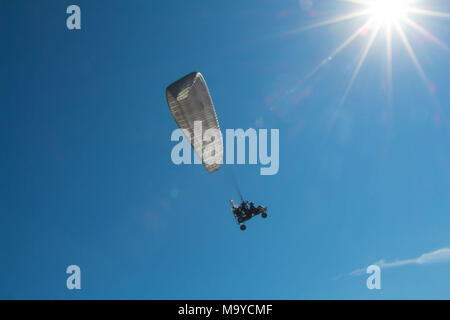 Due persone su un paraplane nel cielo blu battenti al sole Foto Stock