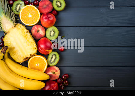 Frutti e bacche. Assortimento di frutta esotica. Vista da sopra con copia spazio. Ananas, pesche, kiwi, agrumi e ciliegio Foto Stock