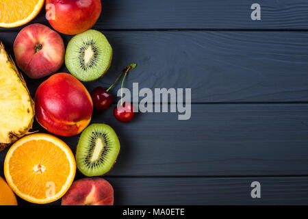 Frutti e bacche. Assortimento di frutta esotica. Cibo sano e background. Ananas, pesche, kiwi, agrumi e ciliegio Foto Stock