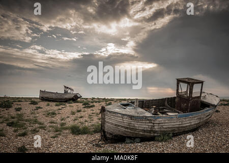 In legno antico barche da pesca a Dungeness nel Kent, non più in servizio che sedersi sulla ghiaia abbandonate al tempo e alla natura. Foto Stock